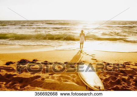 Rear view of a woman standing on the beach View Large Photo Image Stock Photo - Rear view of a woman standing on the beach. Fotosearch
