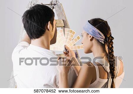 Stock Image - Rear view of a young couple choosing color from a color swatch. Fotosearch