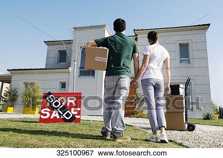 Rear view of a young couple looking at a house View Large Photo Image Stock Photo - Rear view of a young couple looking at a house. Fotosearch