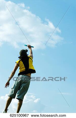 Rear view of a young man playing with a plastic disc View Large Photo Image Stock Photo - Rear view of a young man playing with a plastic disc. Fotosearch