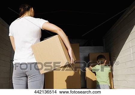 Rear view of a young woman carrying a cardboard box View Large Photo Image Picture - Rear view of a young woman carrying a cardboard box. Fotosearch