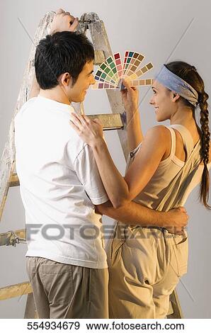 Rear view of a young woman showing color swatch to a young man View Large Photo Image Stock Photo - Rear view of a young woman showing color swatch to a young man. Fotosearch