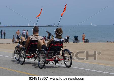 Stock Photo - Rear view of two men on a tricycle, Oak Street Beach, Lake Shore Drive, Chicago, Illinois, USA. Fotosearch