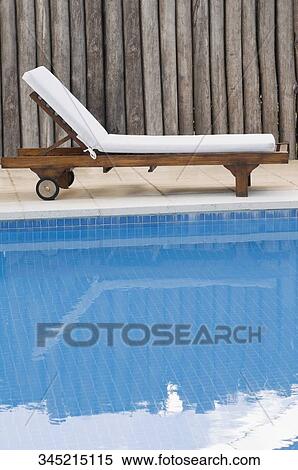 Stock Photography - Reclining chair at the poolside. Fotosearch
