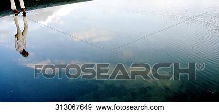 Stock Photo - Reflection of a man in water, Iceland. Fotosearch