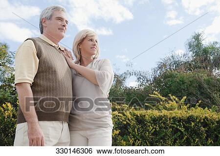 Senior man standing with a mature woman in a park View Large Photo Image Stock Photograph - Senior man standing with a mature woman in a park. Fotosearch