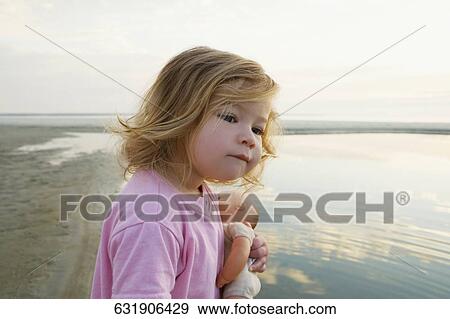 Side profile of a baby girl holding a doll and looking away View Large Photo Image Stock Photo - Side profile of a baby girl holding a doll and looking away. Fotosearch