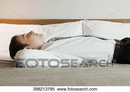Side profile of a businessman lying on the bed and thinking View Large Photo Image Stock Photography - Side profile of a businessman lying on the bed and thinking. Fotosearch