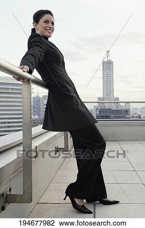 Side profile of a businesswoman leaning against a railing and smiling View Large Photo Image Stock Image - Side profile of a businesswoman leaning against a railing and smiling. Fotosearch