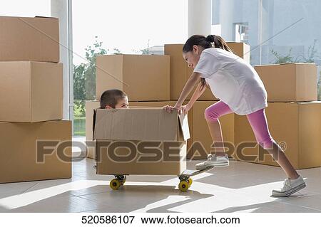 Side profile of a girl pushing a cardboard box with his brother View Large Photo Image Stock Photo - Side profile of a girl pushing a cardboard box with his brother. Fotosearch