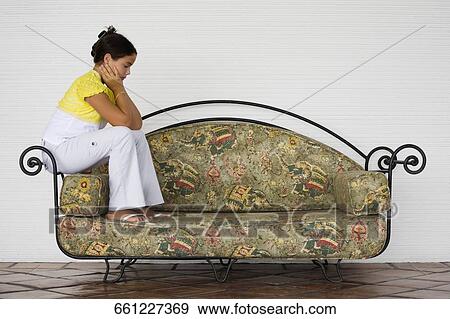 Side profile of a girl sitting on the edge of a couch View Large Photo Image Stock Photo - Side profile of a girl sitting on the edge of a couch. Fotosearch