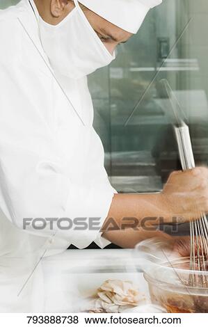 Side profile of a male chef preparing food View Large Photo Image Stock Photo - Side profile of a male chef preparing food. Fotosearch