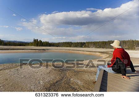 Side profile of a man sitting on a pier at a hot spring, Grand Prismatic Spring, Yellowstone National Park, Wyoming, USA View Large Photo Image Stock Photograph - Side profile of a man sitting on a pier at a hot spring, Grand Prismatic Spring, Yellowstone National Park, Wyoming, USA. Fotosearch