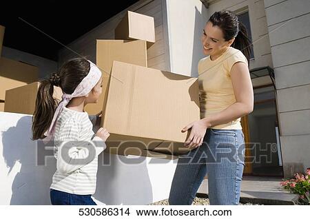 Picture - Side profile of a mature woman and her daughter carrying a cardboard box. Fotosearch