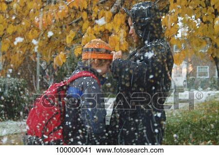 Stock Image - Side profile of a mature woman adjusting the knit hat of her daughter. Fotosearch