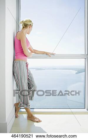 Stock Image - Side profile of a mid adult woman looking out through a window. Fotosearch