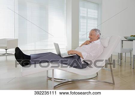 Stock Image - Side profile of a senior man using a laptop and smiling. Fotosearch