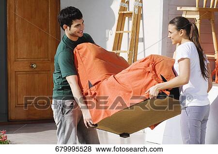 Side profile of a young couple carrying an armchair View Large Photo Image Stock Photo - Side profile of a young couple carrying an armchair. Fotosearch