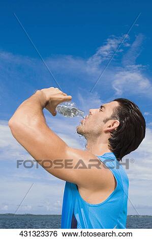 Side profile of a young man drinking water from a water bottle View Large Photo Image Stock Photograph - Side profile of a young man drinking water from a water bottle. Fotosearch
