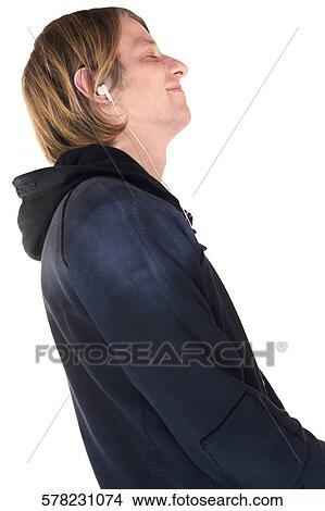 Picture - Side profile of a young man listening to music with earbuds and smiling. Fotosearch