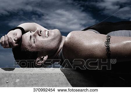Side profile of a young man lying on a ledge and smiling View Large Photo Image Picture - Side profile of a young man lying on a ledge and smiling. Fotosearch
