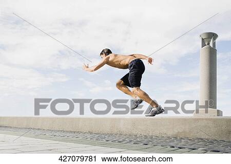 Side profile of a young man running on the ledge View Large Photo Image Stock Image - Side profile of a young man running on the ledge. Fotosearch