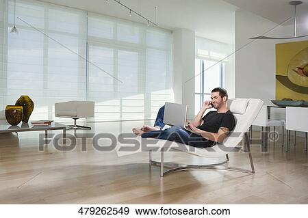 Side profile of a young man using a laptop and talking on a mobile phone View Large Photo Image Stock Photo - Side profile of a young man using a laptop and talking on a mobile phone. Fotosearch
