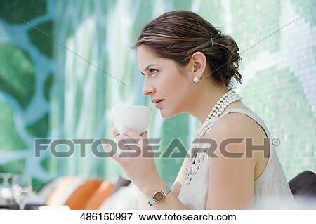 Stock Photo - Side profile of a young woman drinking tea. Fotosearch