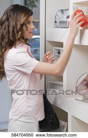 Side profile of a young woman holding a bottle of cosmetics View Large Photo Image Stock Image - Side profile of a young woman holding a bottle of cosmetics. Fotosearch