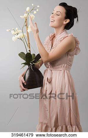Side profile of a young woman holding a flower pot and smiling View Large Photo Image Stock Photo - Side profile of a young woman holding a flower pot and smiling. Fotosearch