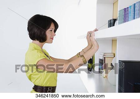 Side profile of a young woman looking at a bookshelf View Large Photo Image Stock Image - Side profile of a young woman looking at a bookshelf. Fotosearch