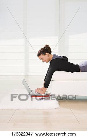 Side profile of a young woman lying on the bed and using a laptop View Large Photo Image Stock Photo - Side profile of a young woman lying on the bed and using a laptop. Fotosearch