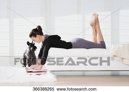 Side profile of a young woman lying on the bed and using a laptop View Large Photo Image Stock Photography - Side profile of a young woman lying on the bed and using a laptop. Fotosearch