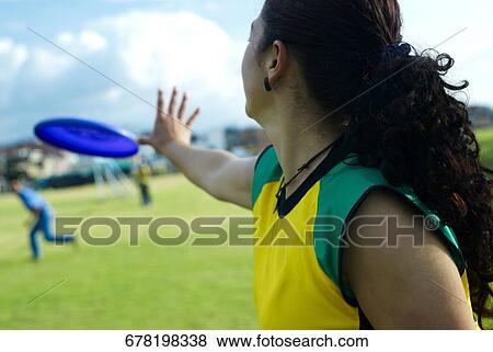 Side profile of a young woman playing with a plastic disc View Large Photo Image Stock Photo - Side profile of a young woman playing with a plastic disc. Fotosearch
