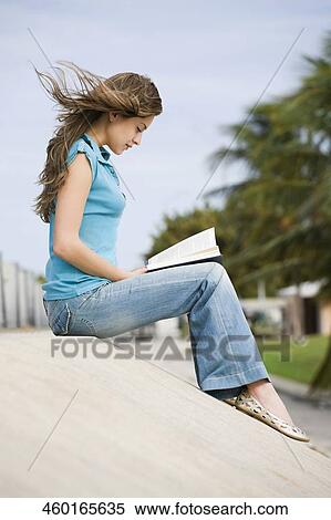 Stock Photography - Side profile of a young woman reading a book. Fotosearch