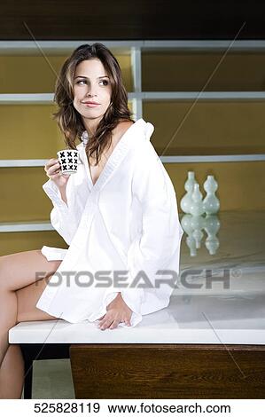 Side profile of a young woman sitting on a table and having tea View Large Photo Image Stock Photo - Side profile of a young woman sitting on a table and having tea. Fotosearch