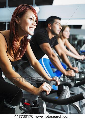 Side profile of three people exercising on exercise bikes View Large Photo Image Stock Image - Side profile of three people exercising on exercise bikes. Fotosearch