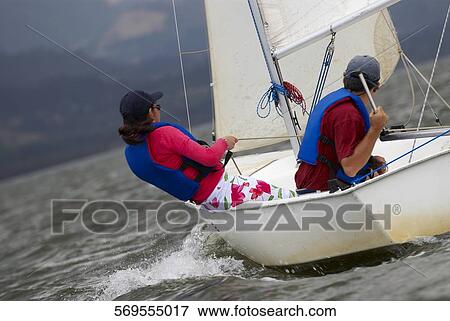 Stock Photo - Side profile of two people participating in a sailboat race. Fotosearch