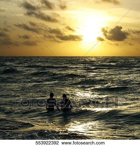 Silhouette of a couple standing in the sea at dusk View Large Photo Image Stock Image - Silhouette of a couple standing in the sea at dusk. Fotosearch