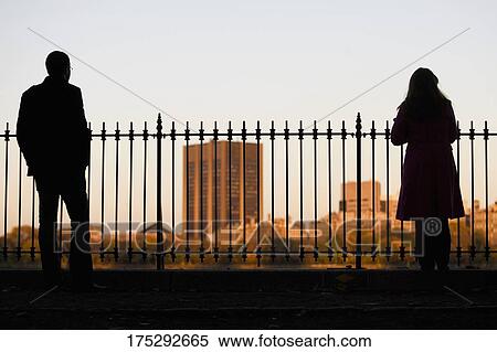 Silhouette of a man and a woman standing near a railing with buildings in the background, Central Park, Manhattan, New York City, New York State, USA View Large Photo Image Stock Photography - Silhouette of a man and a woman standing near a railing with buildings in the background, Central Park, Manhattan, New York City, New York State, USA. Fotosearch