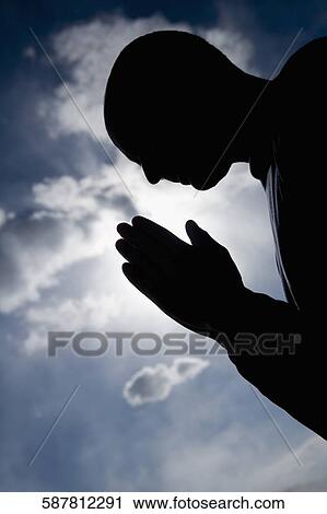 Silhouette of a man in a prayer position View Large Photo Image Stock Image - Silhouette of a man in a prayer position. Fotosearch