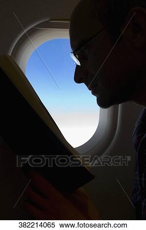 Silhouette of a man reading a book in an airplane View Large Photo Image Stock Photography - Silhouette of a man reading a book in an airplane. Fotosearch