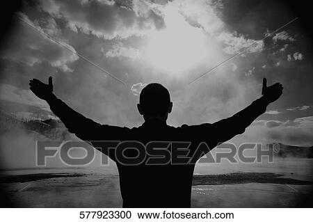 Stock Image - Silhouette of a man with his arms outstretched, Grand Prismatic Spring, Yellowstone National park, Wyoming, USA. Fotosearch