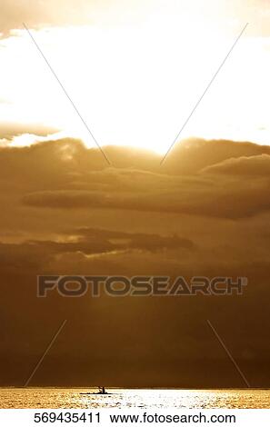 Stock Image - Silhouette of a person rowing a boat, Tahiti, French Polynesia. Fotosearch