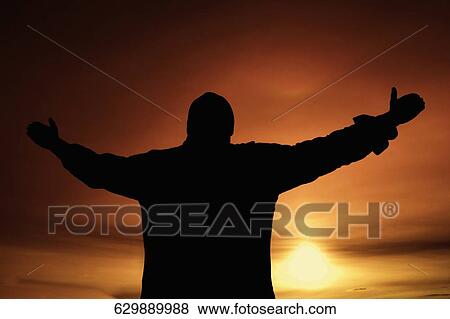 Silhouette of a person standing with arms raised View Large Photo Image Stock Photo - Silhouette of a person standing with arms raised. Fotosearch