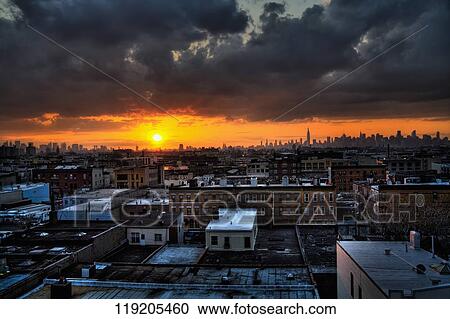Stock Image - Strom clouds over a cityscape at sunrise. Fotosearch