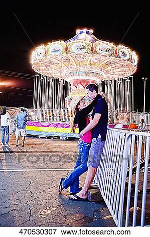 Teenage couple embracing each other in an amusement park View Large Photo Image Stock Photo - Teenage couple embracing each other in an amusement park. Fotosearch