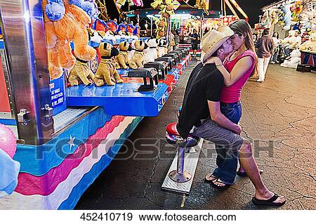 Teenage couple kissing each other in an amusement park View Large Photo Image Stock Photo - Teenage couple kissing each other in an amusement park. Fotosearch