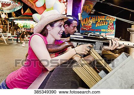 Stock Image - Teenage couple shooting in an amusement park. Fotosearch
