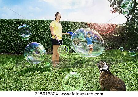 Teenage girl making giant bubble in a park View Large Photo Image Picture - Teenage girl making giant bubble in a park. Fotosearch